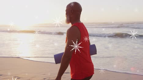 Animation-of-christmas-snow-falling-over-senior-african-american-man-on-beach