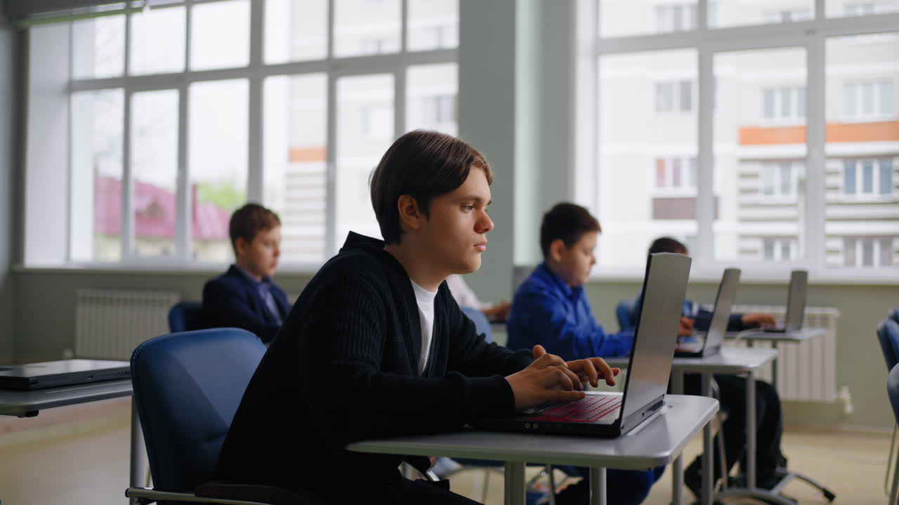 estudiantes trabajando en computadoras portátiles en un aula