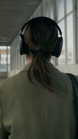 woman walking in a modern building wearing headphones