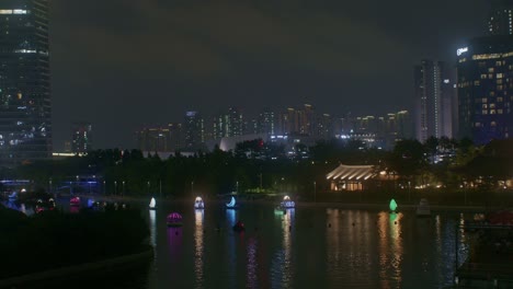 Wunderschöner-Romantischer-Nachtparkblick-Mit-Fluss-In-Der-Stadt,-Stadtlichtern-Und-Booten,-Panoramaaussicht-Auf-Das-Stadtbild-Aus-Einem-Hohen-Winkel
