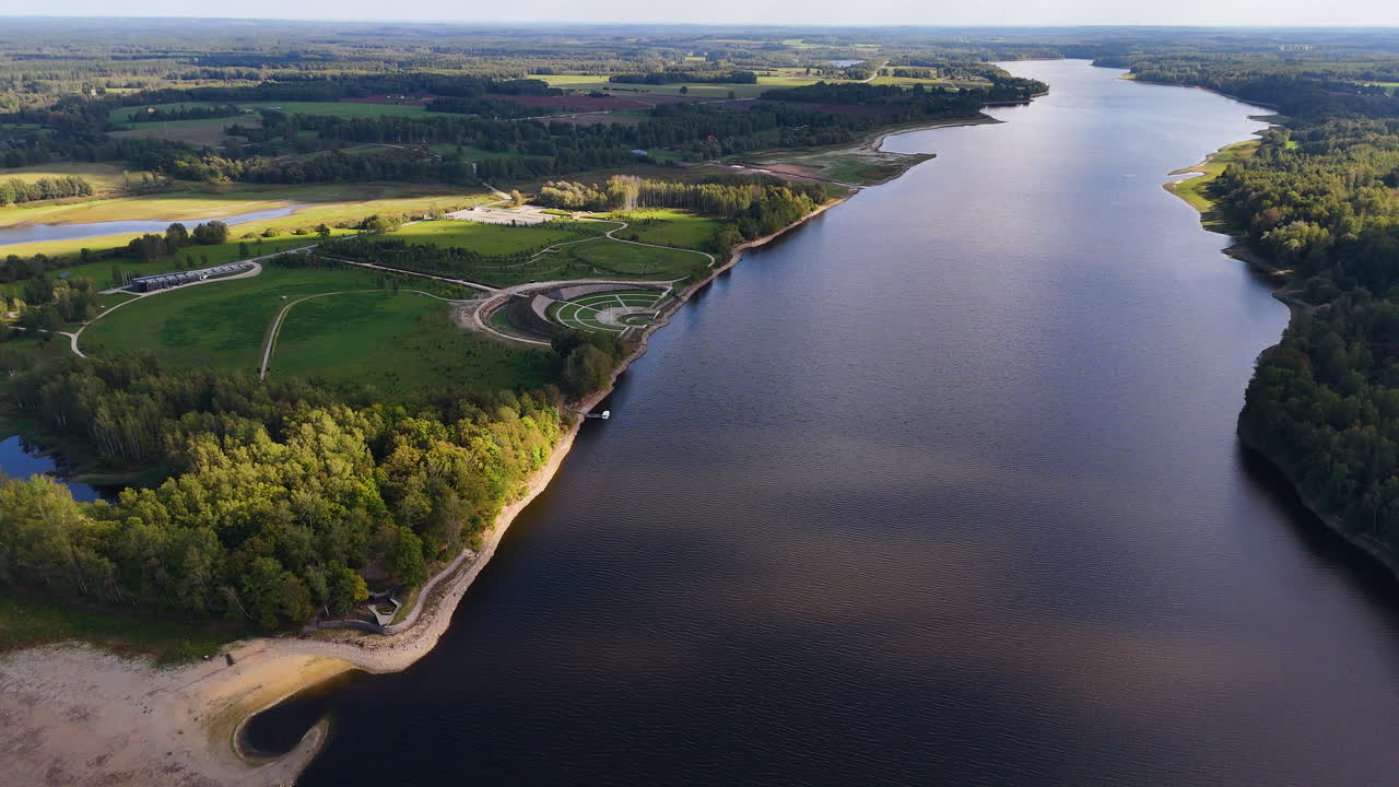 un avión volando hacia atrás sobre el río daugava, el jardín del destino a la izquierda, letonia