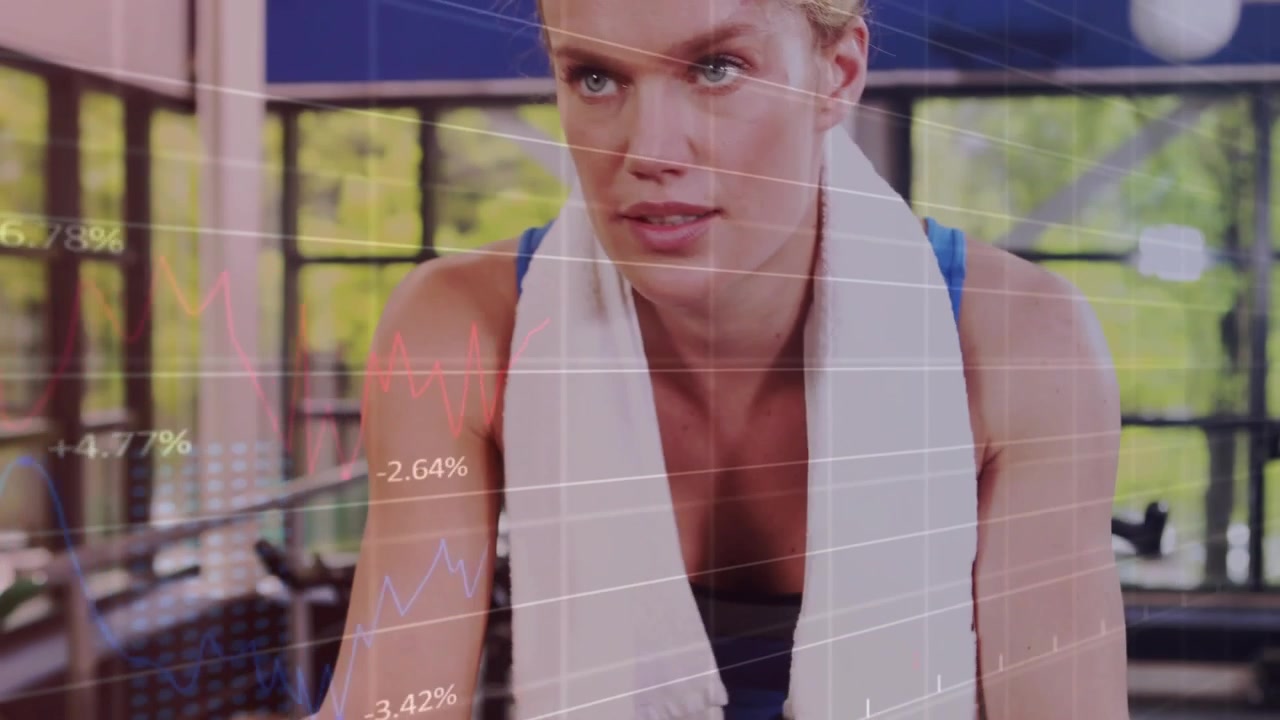 La telecamera panoramica rivela una donna che pedala in palestra, attivando una sovrapposizione che mostra i dati percentuali di monitoraggio dello sforzo.