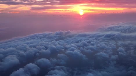 flying above clouds and a sea beneath it with a colourful sunset on the horizon