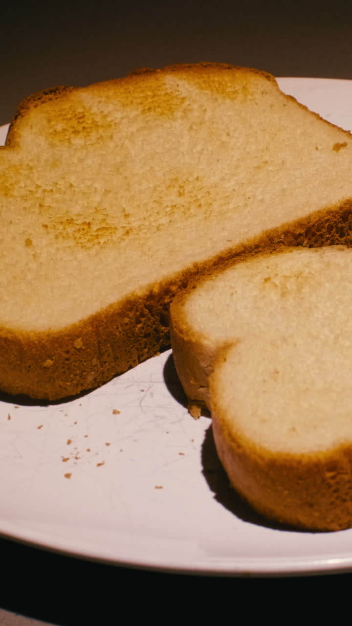 Close up of freshly toasted white bread on a ceramic plate with crumbs. Perfect for breakfast, healthy eating, and morning routine