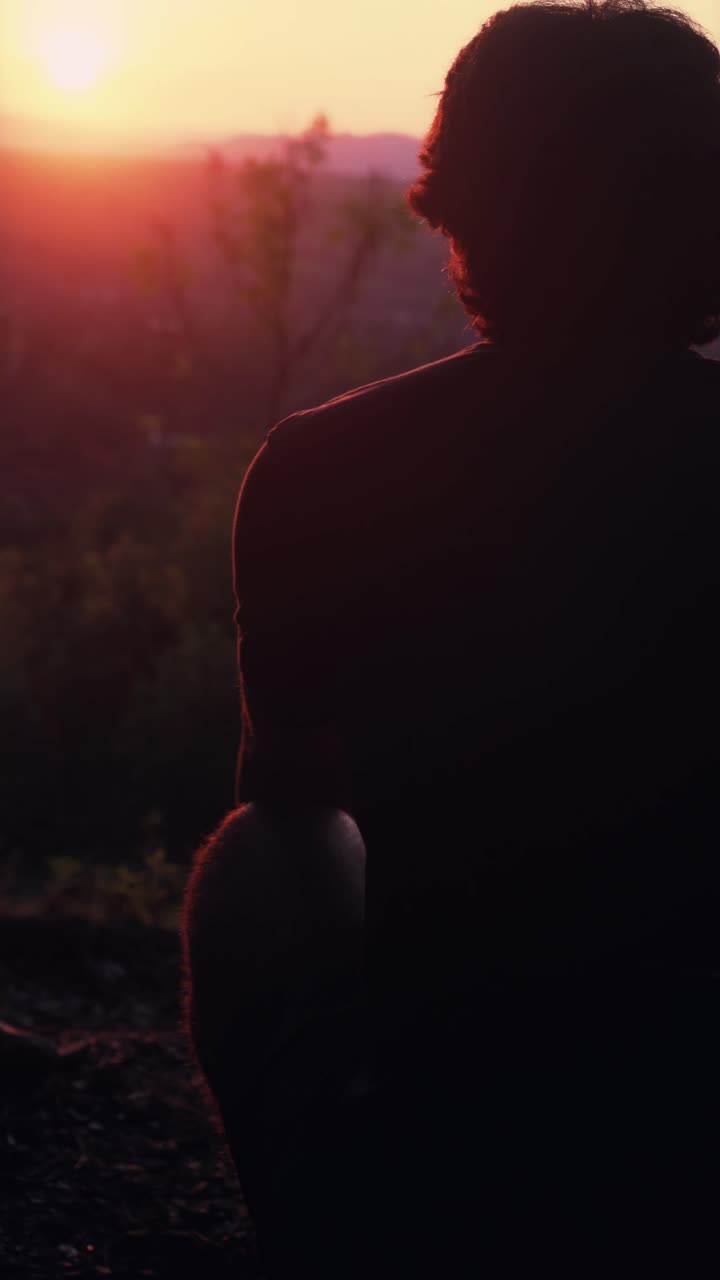 Silhueta de Pessoa Sentada Observando o Pôr do Sol Sobre Montanhas