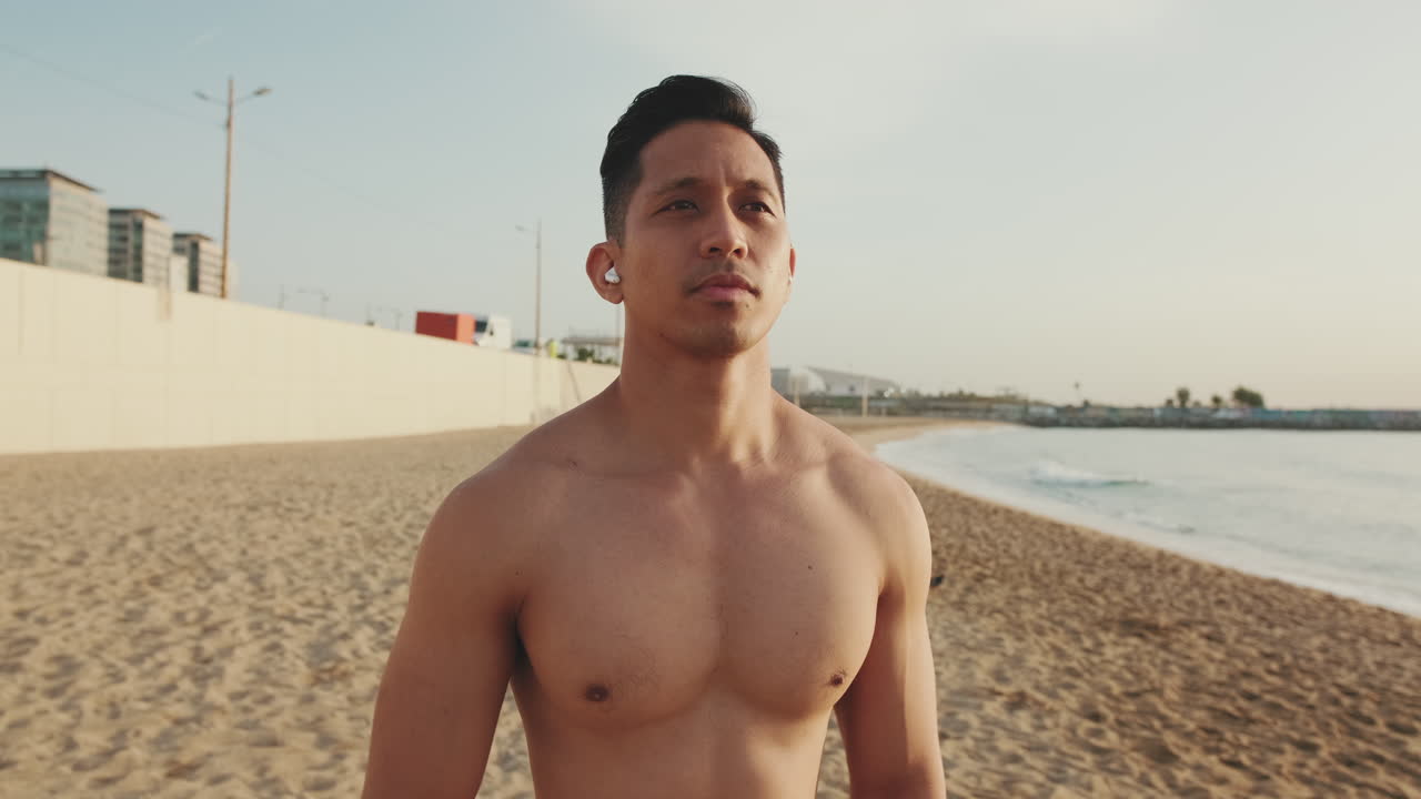 Man on the beach stretching his neck while listening to music
