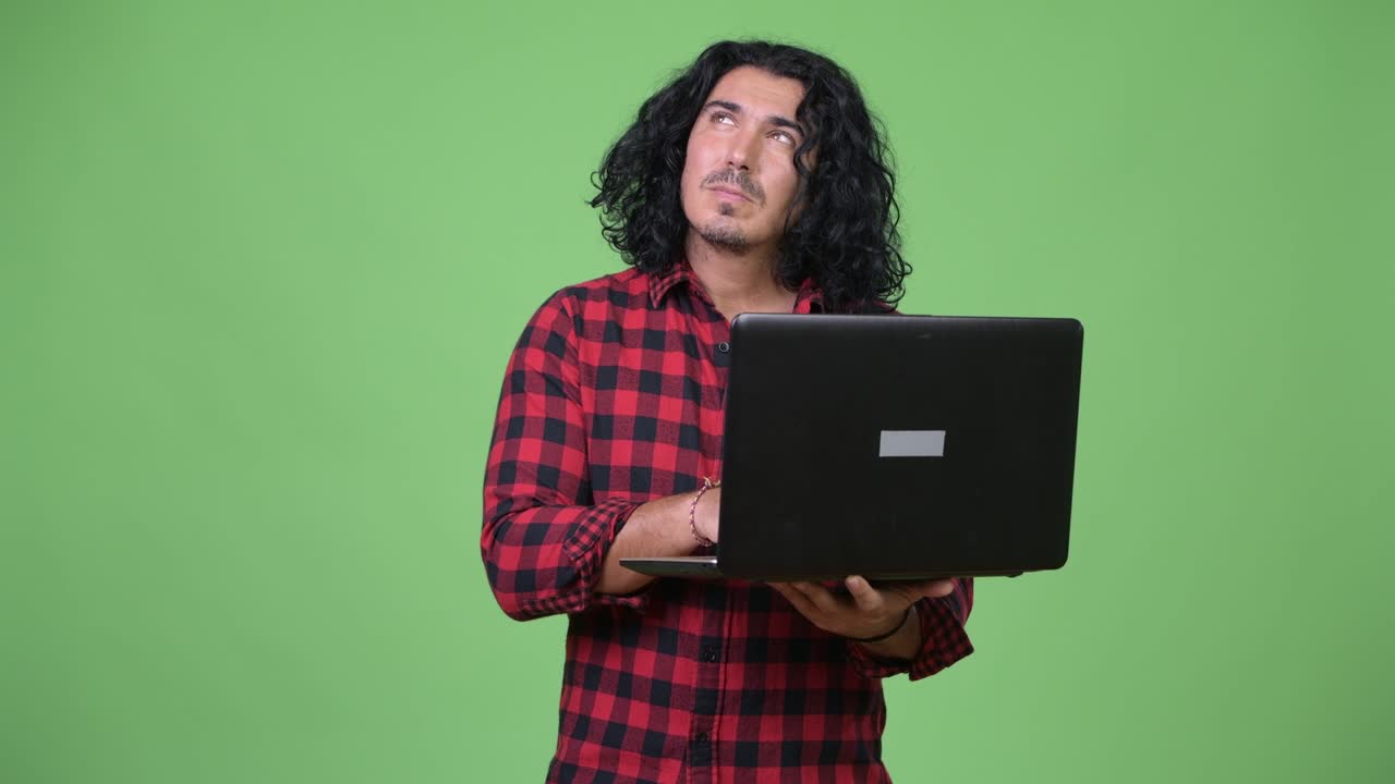 Handsome hipster man thinking while using laptop