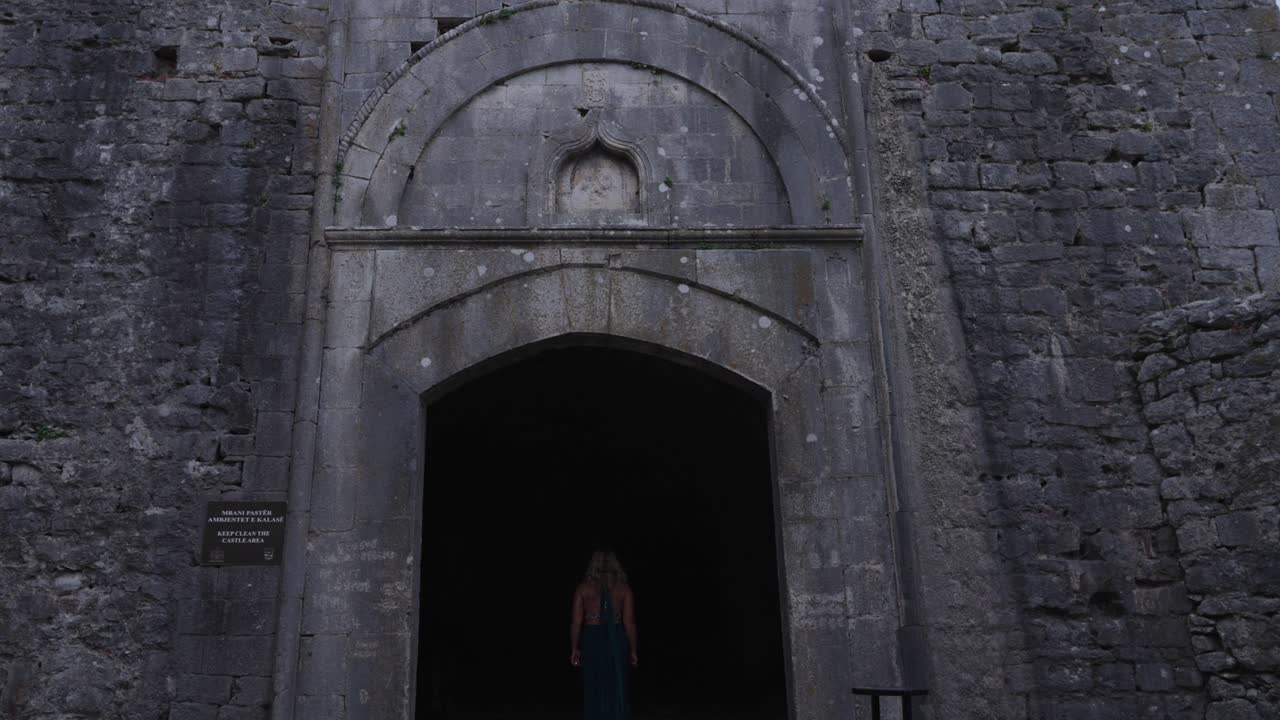 Back View Of A Woman Entering Historic Rozafa Castle. - wide shot