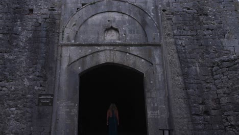 back view of a woman entering historic rozafa castle. - wide shot