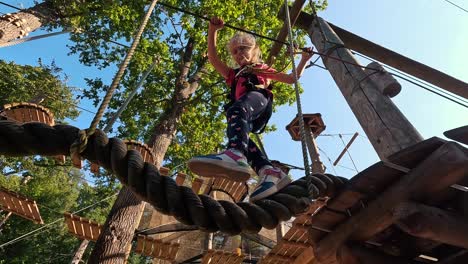 Glückliches-Kleines-Mädchen,-Das-In-Der-Tarzan-Attraktion-Auf-Dem-Spielplatz-Im-Vergnügungspark-Spielt