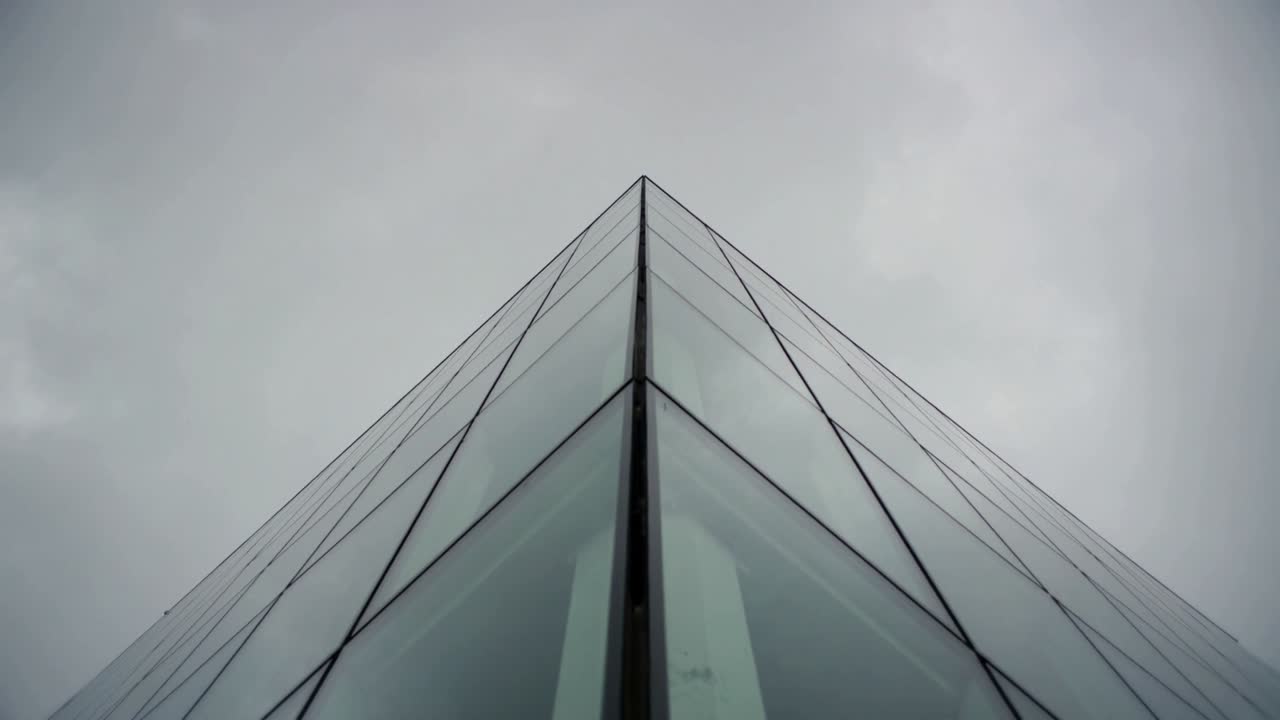Recording glass-clad apex reflecting with clouds shifting, camera fixed at ground, showing mullions