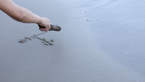 dibujando letras a mano en la playa de arena.