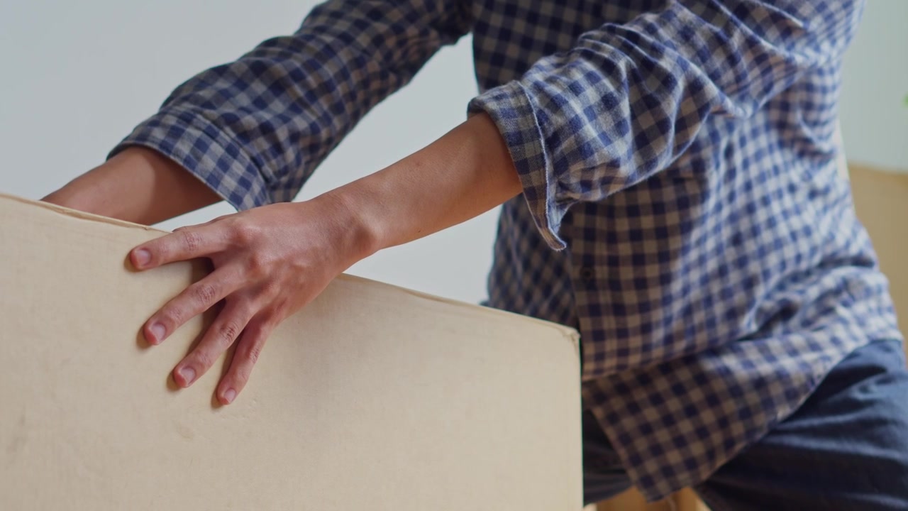 Man actively sliding or pushing large cardboard box across floor during move