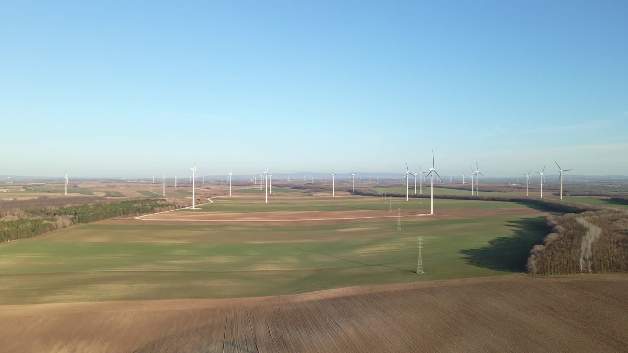 Drone footage of a wind farm with multiple turbines in rural landscape