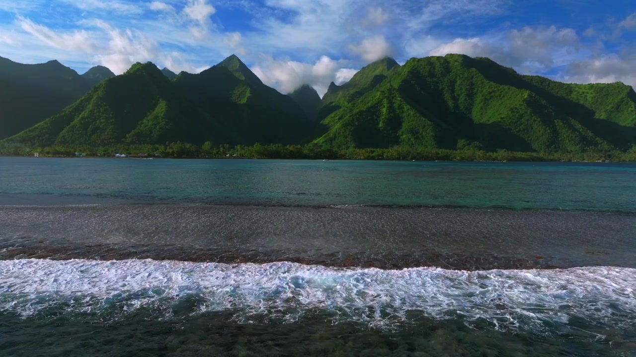 Coral reef Teahupo'o surf waves sunny blue sky South Pacific Ocean drone Tahiti French Polynesia harbor view landscape waves crashing island Passe Havea mountainous ridge volcano peaks forward pan up
