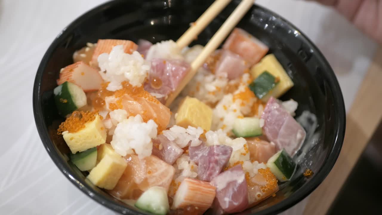 젓가락을 사용하여 바라 시라시 덮밥을 신선하게 먹다