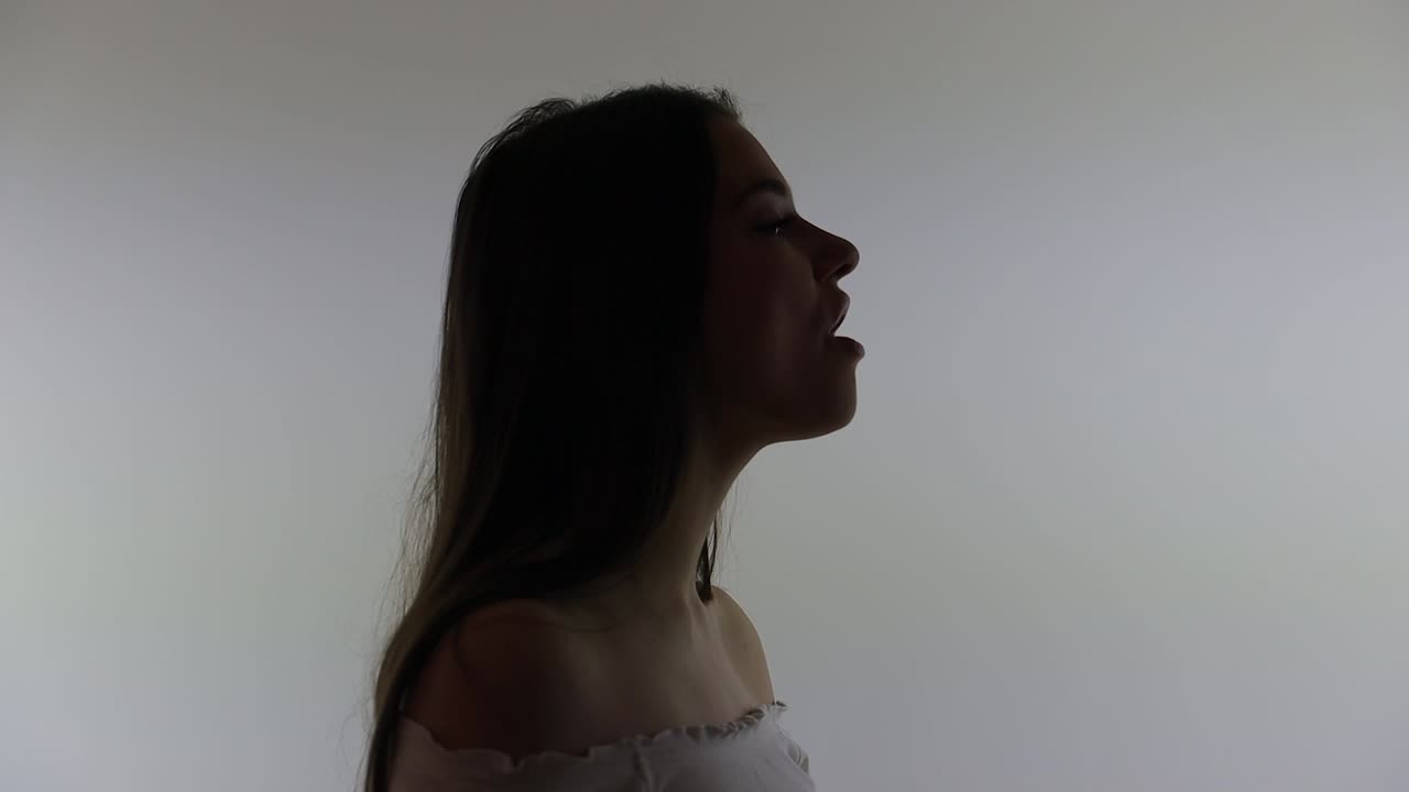 작물 위에서 노래하는 매력적인 젊은 여성의 실루 ⁇