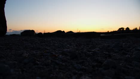 vista de las piernas del hombre mientras camina por la playa de piedra, cámara lenta