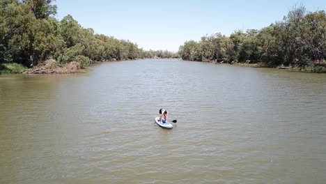 Drohnenantenne-über-Dem-Fluss-Frau,-Die-Auf-Dem-Stand-Up-Paddle-Board-Steht