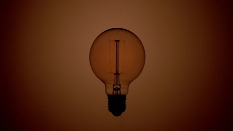 tungsten light bulb blinking over a warm light background.