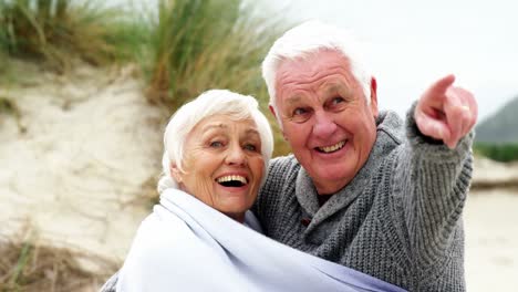 happy senior couple pointing at view
