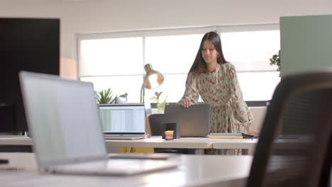 Mujer-De-Negocios-Casual-Birracial-Cerrando-Laptop-En-La-Oficina,-Cámara-Lenta