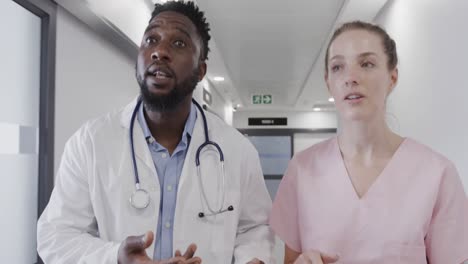 Diverse-female-nurse-and-male-doctor-talking-in-corridor-then-running-urgently,-slow-motion