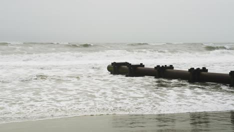 rough ocean waves hitting pipeline on beach on a gloomy day in ocnj