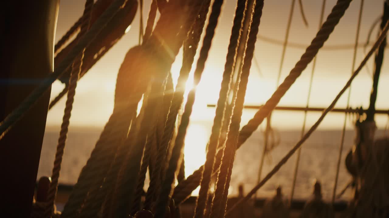 Alba che splende attraverso le manovre di una nave a vela su un tradizionale veliero in mare.