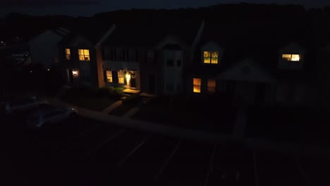 aerial night view of american suburban neighborhood with glowing house windows and streetlights. peaceful, cozy atmosphere perfect for themes like home life, evening, or small-town america. rising.