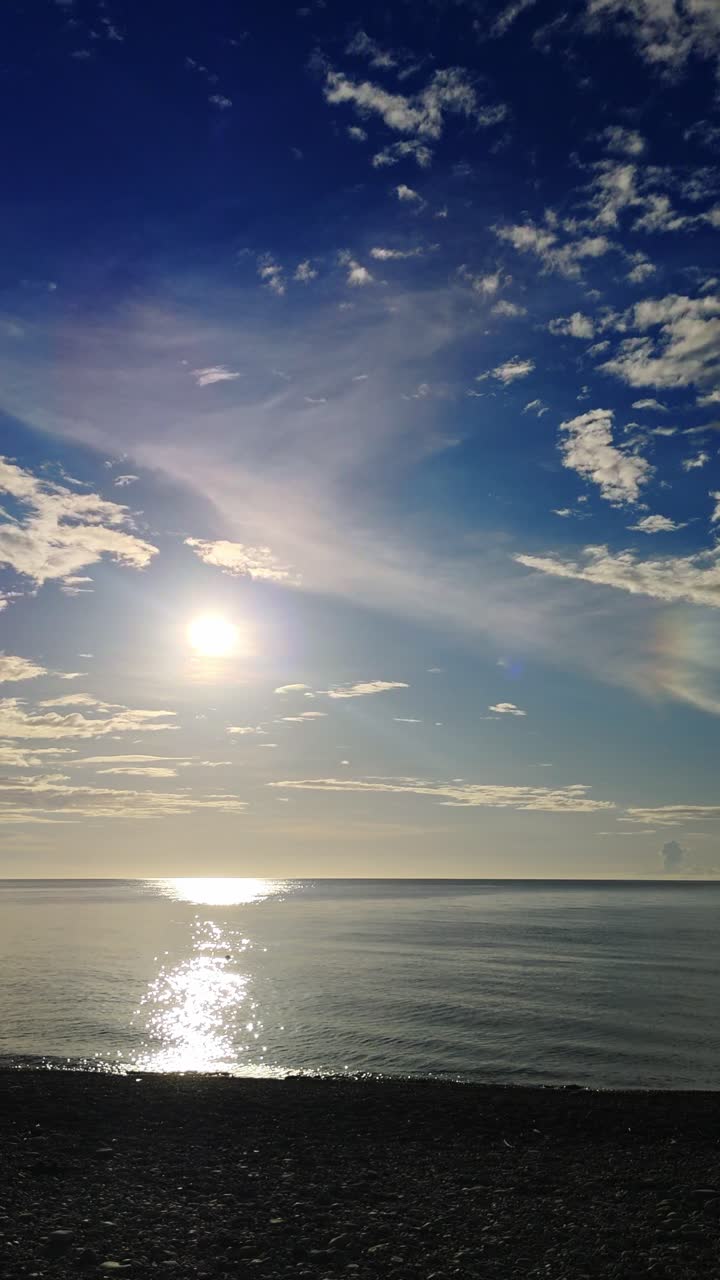 Capturing the serene beauty of Mabua Pebble Beach in Surigao Del Norte, Philippines, this vertical video shot during the late afternoon showcases calm waters, pebbles, and a cloudy sky.