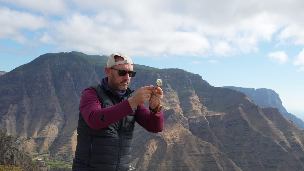 Man using compass and looking at landscape while hiking in the mountains. Gran Canaria, Canary Islands.