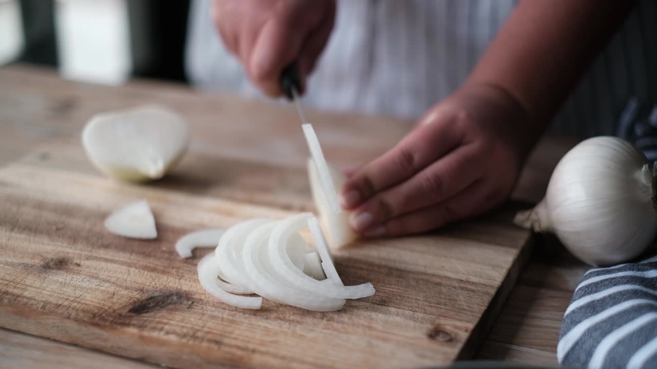 Chef cutting an onion with a knife.