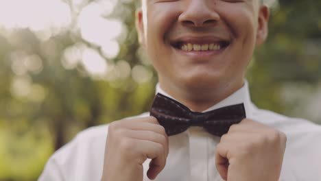 Handsome-groom-fixes-his-bow-tie.-Close-up-shot.-Wedding-morning.