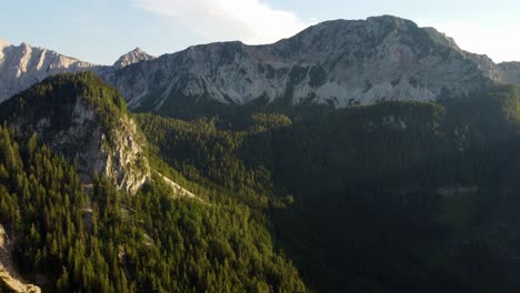 Aerial-view-of-a-high-mountain-forested-saddle-near-rocky-mountain-peaks