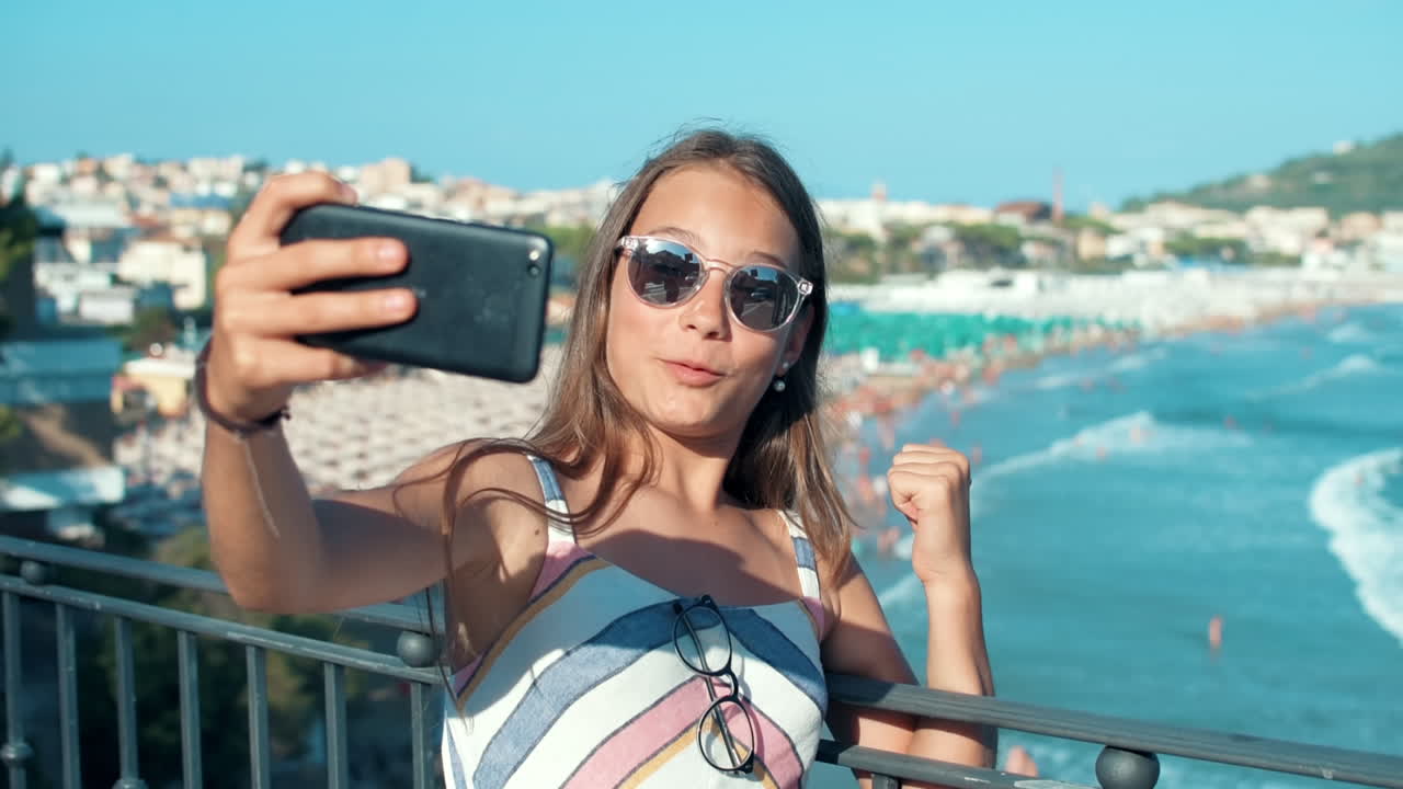 niña alegre haciendo una videollamada al aire libre. adolescente disfrutando de un día de verano en la costa
