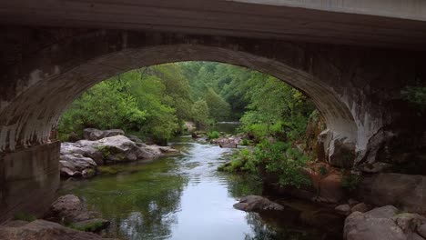 Drone-Volando-Bajo-El-Puente-De-Piedra-De-Arco-En-La-Naturaleza