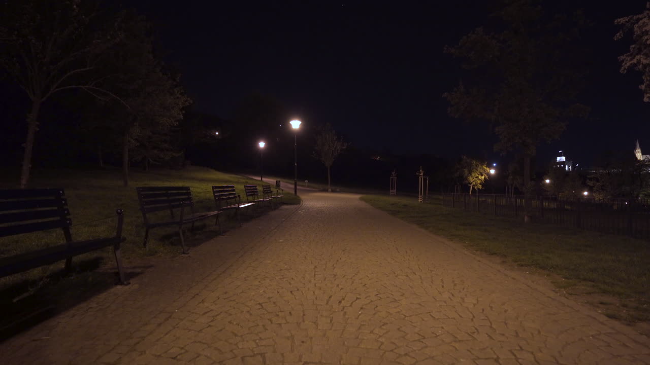 bancos a lo largo del pavimento en el parque petrin por la noche, praga, chequia, durante el cierre