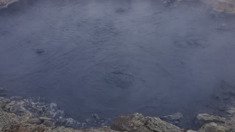 Dark-blue-geothermal-mud-pool-with-steam-at-Myvatn-Geothermal-Area,-Iceland