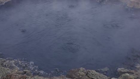 dark blue geothermal mud pool with steam at myvatn geothermal area, iceland