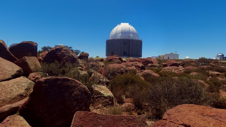 En langsom, filmisk panorering af SALT-bygningen (South African Large Telescope) i Sutherland. Observatoriets massive hvide geodesiske kuppel står i kontrast til de robuste røde klipper i Karoo.