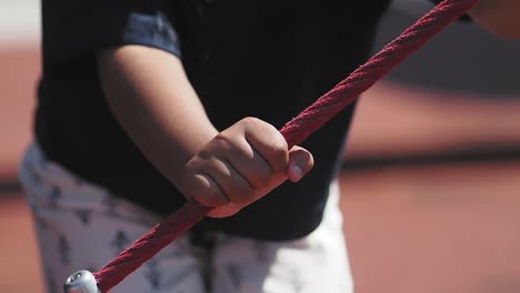 child's hand holding rope