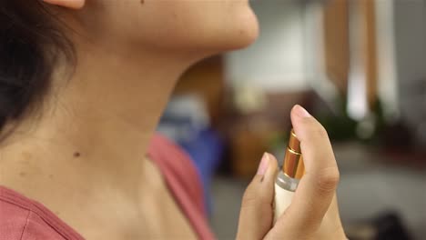 beautiful young woman gently spray perfume around her neck on bathroom