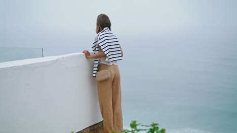 girl looking seaside view on cliff top. summer tourist admiring ocean landscape