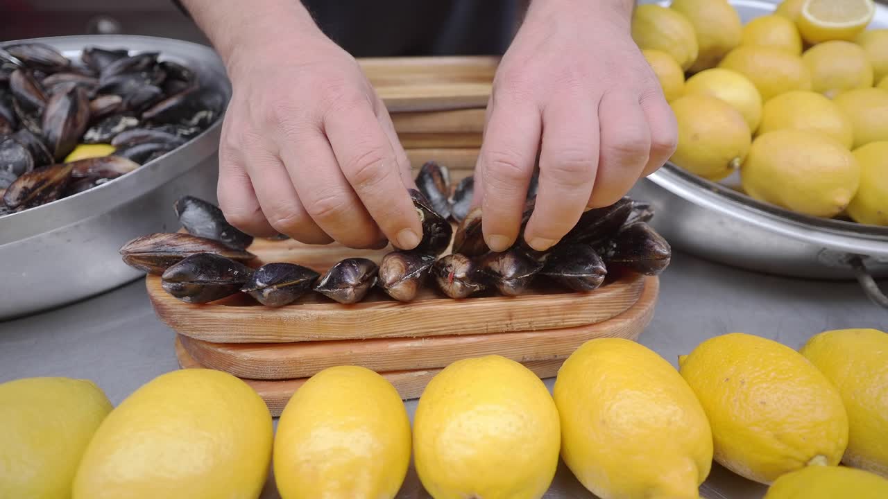 Close Up of Hands Preparing Fresh Mussels with Lemons