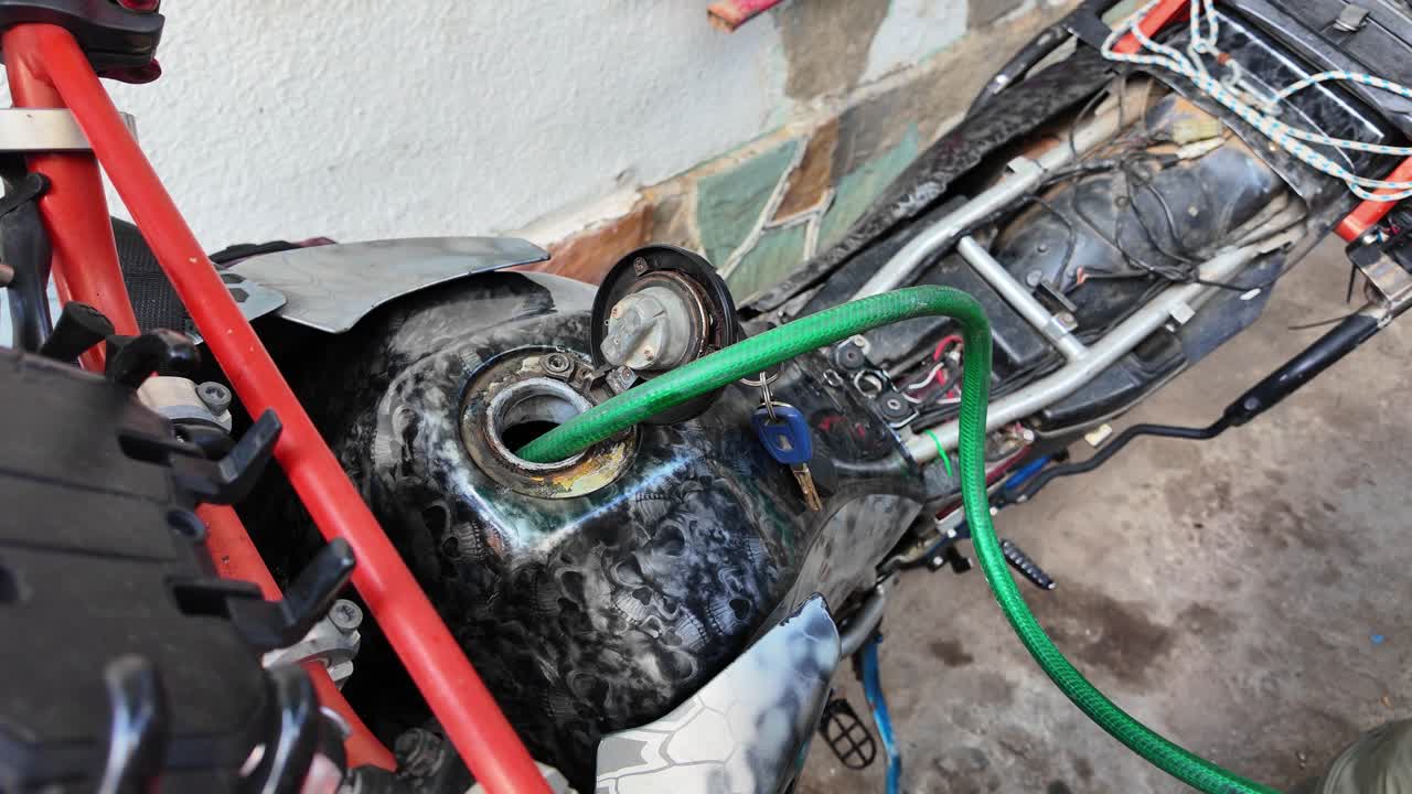 manual process of adding fuel to a motorcycle's exposed tank, illustrating DIY maintenance or emergency refueling