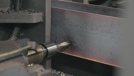 automated machine drilling metal beams with a drill slow motion close shot