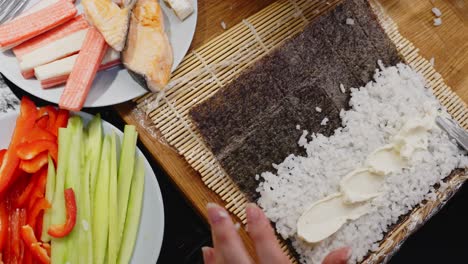 Person-Spreading-Cream-Over-Rice-All-Over-With-Knife,-Preparing-Sushi-Roll,-Homemade