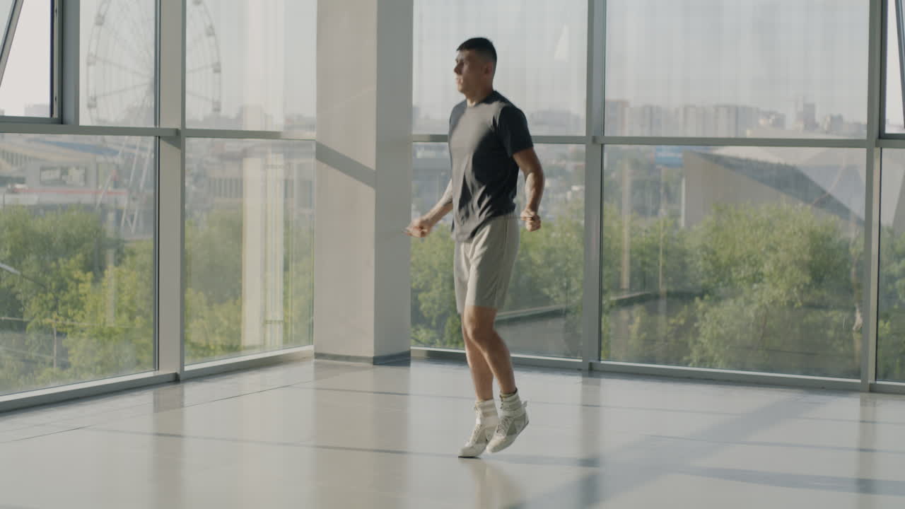 Man Jumping Rope in Modern Gym with City View