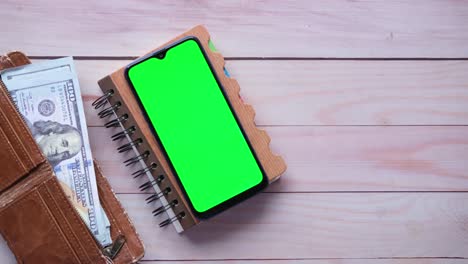smartphone, wallet, and notebook on wooden table